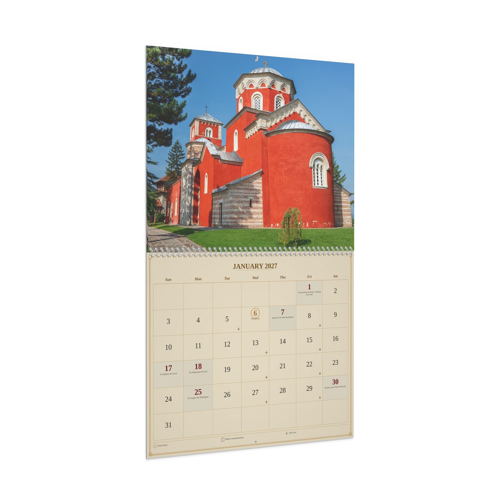 A spiral-bound desk calendar page featuring a large photograph of a red church building on the top half and a January 2027 calendar grid on the bottom half, shown against a plain white background.